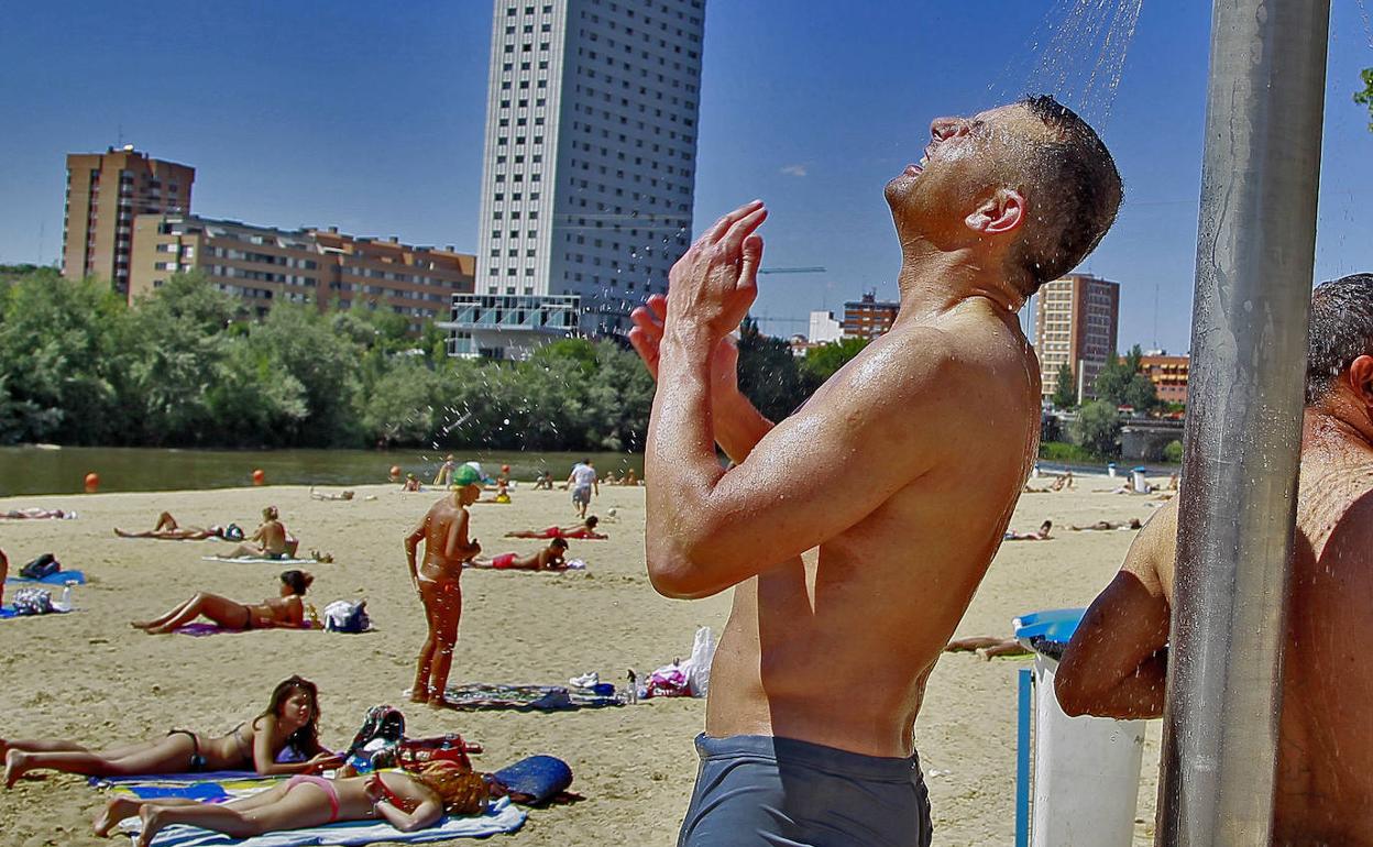 Un bañista mitiga las altas temperaturas en las duchas de la playa de las Moreras. 